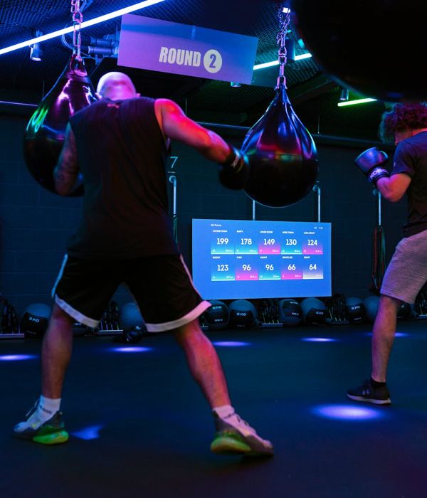 Man performing a controlled strength exercise in a modern gym with magenta light.